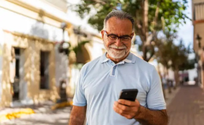 Persona mayor sonriente usando una app financiera en su móvil para planificar su jubilación en España