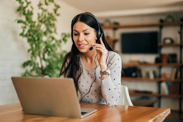 Mujer trabajando desde casa con auriculares y agenda, representando el trabajo de asistente virtual online