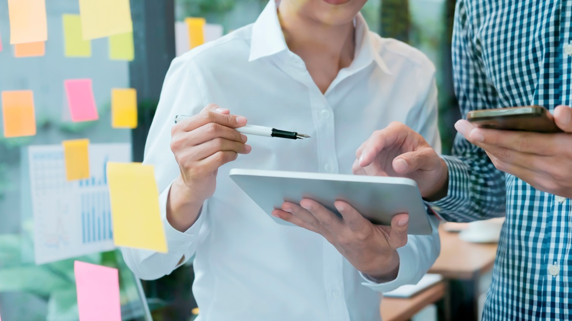 Dos inversores revisando estrategias de diversificación de cartera en una tablet y smartphone, planificando inversiones en España con enfoque a largo plazo