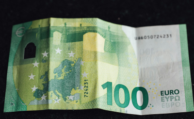 Billete de 100 euros sobre una mesa, representando la estrategia de inversión mensual de 100 € en España.