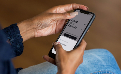 Persona utilizando su smartphone para gestionar sus finanzas personales y ahorro mediante una app en España