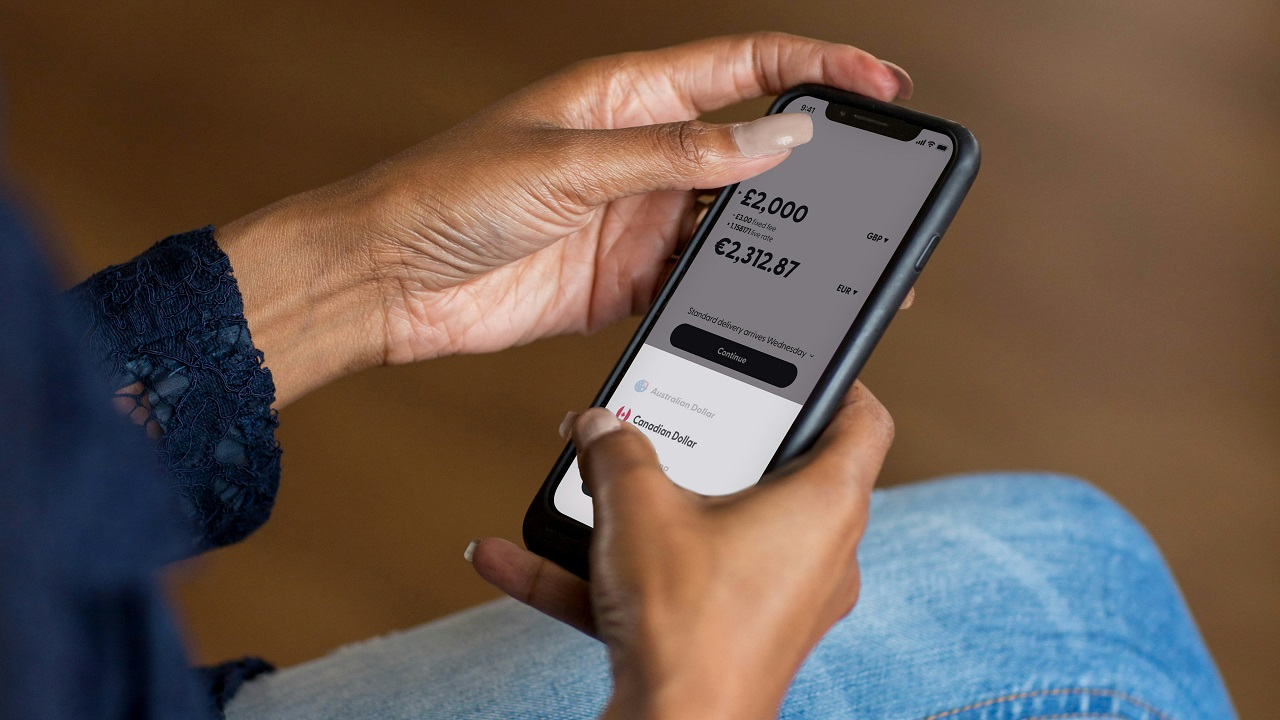 Persona utilizando su smartphone para gestionar sus finanzas personales y ahorro mediante una app en España