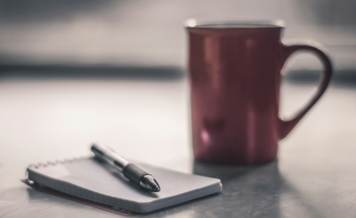Fotografía minimalista de una mesa con una taza de café y un cuaderno, simbolizando el minimalismo financiero en España