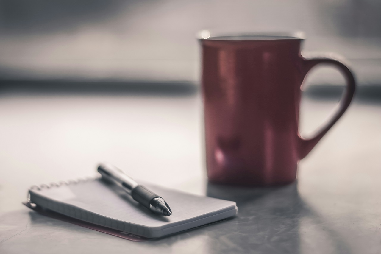 Fotografía minimalista de una mesa con una taza de café y un cuaderno, simbolizando el minimalismo financiero en España
