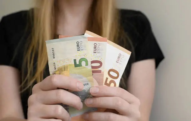 Una mano sostiene una pequeña cantidad de billetes, simbolizando que no se necesita mucho dinero para empezar a invertir en la bolsa en España.