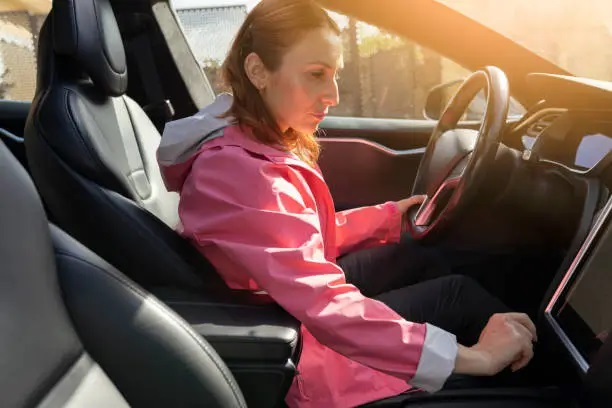 Mujer conduciendo un coche eléctrico aplicando técnicas de conducción eficiente para reducir el consumo energético.