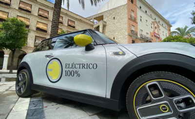 Coche eléctrico 100 % circulando por una ciudad española en 2025, representando la movilidad sostenible y el menor coste por kilómetro frente a gasolina y diésel.