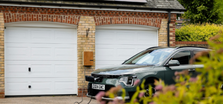 Coche eléctrico cargando en el garaje de una vivienda española en 2025, simbolizando el bajo coste de carga doméstica frente a puntos públicos.