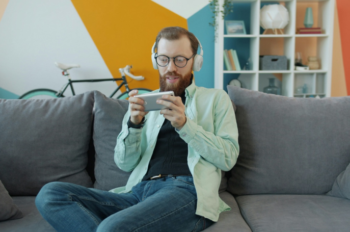 Persona jugando con el móvil en casa mientras gana dinero real a través de apps en España 2025.